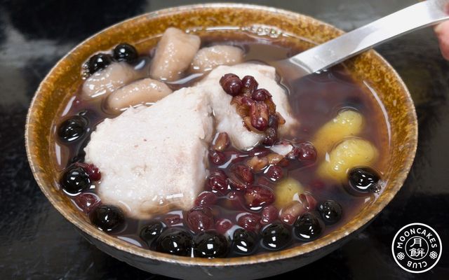 Two large chunk of taros, with pearls, red bean, taro dumplings, and sweet potato dumplings in a bowl of red bean soup.